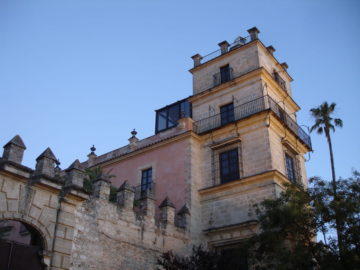 Fachada do Alcázar de Jerez, com muralha de pedra e torre