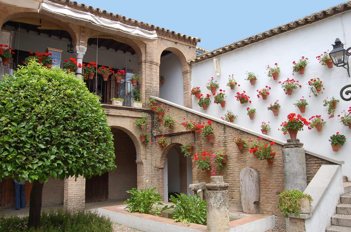 Patio cordobês com vasos de flores e paredes caiadas