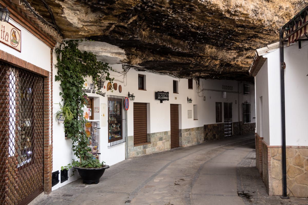 Rua de Setenil coberta pela saliência de rocha, com casas brancas dos dois lados