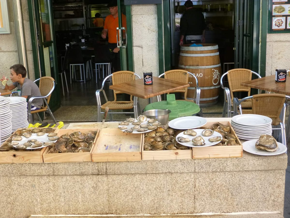 Balcão de pedra com bandejas de ostras diante de um bar, na rua das ostras de Vigo